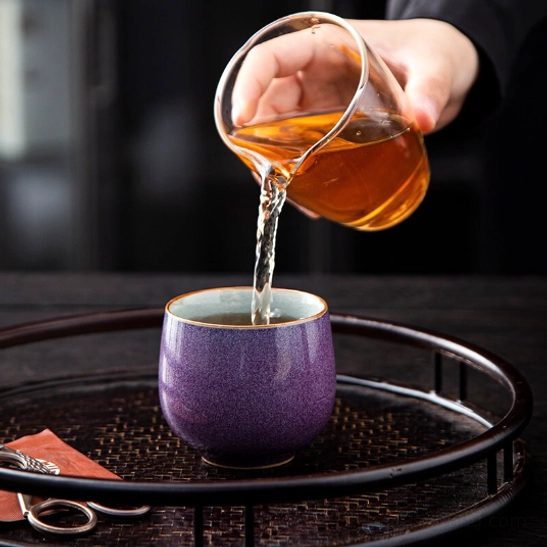 purple crackle glaze Chinese porcelain tea cup held in hand to show grip