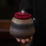full view of dark brown sealed ceramic tea storage canister with red fabric lid