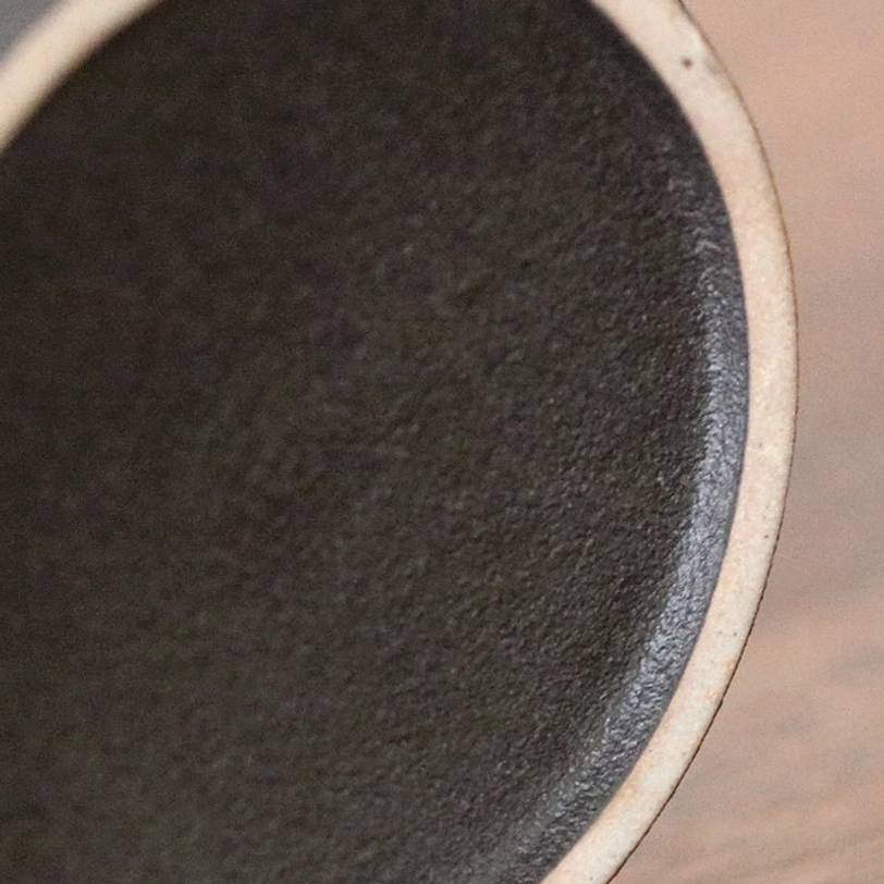 Side view of black matte ceramic tea storage canister with wood lid