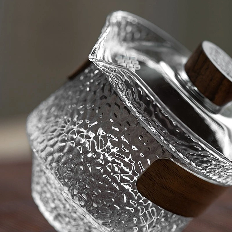 side view of empty clear glass gaiwan with dark wood trim