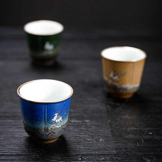 single red ceramic tea cup with traditional deer motif side view