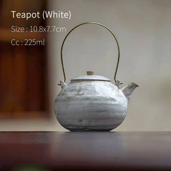 Standalone white ceramic teapot with brass handle and built-in infuser