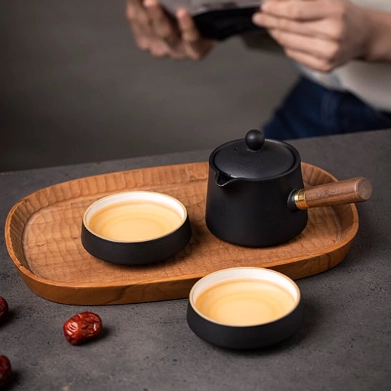 two teacups placed beside teapot of 190ml black ceramic travel tea set