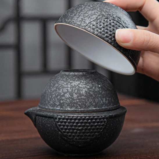 Travel tea set packed in closed black travel bag with leather carry strap