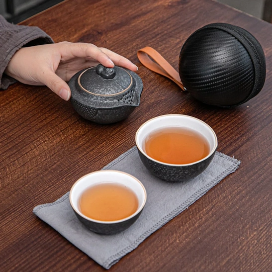 Close up of teapot textured surface and golden decorative line of travel tea set