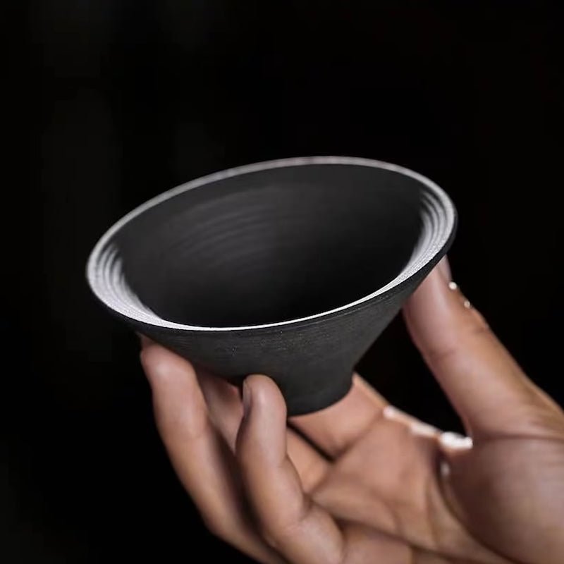 Two black clay tea cups stacked for size comparison