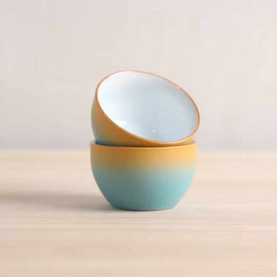 two ceramic chinese tea bowls held in hands showing ergonomic shape