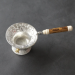 Full view of vintage engraved silver tone tea strainer with bamboo handle