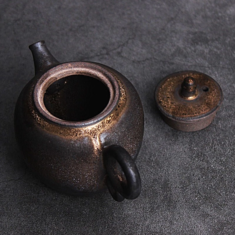 front view of vintage gilded ceramic teapot showing spout and handle