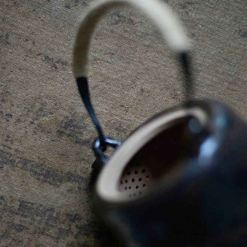 Close up of jute wrapped metal handle on wabi-sabi ceramic teapot