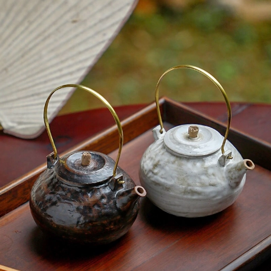 White ceramic teapot with infuser resting on matching white tea warmer stove