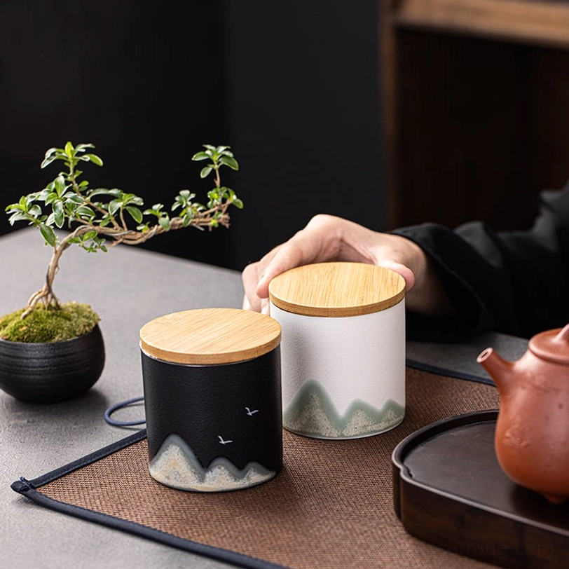 white ceramic tea storage canister on wooden surface with green landscape design