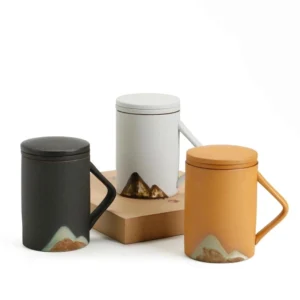 side view of yellow ceramic tea infuser mug with mountain design and strainer