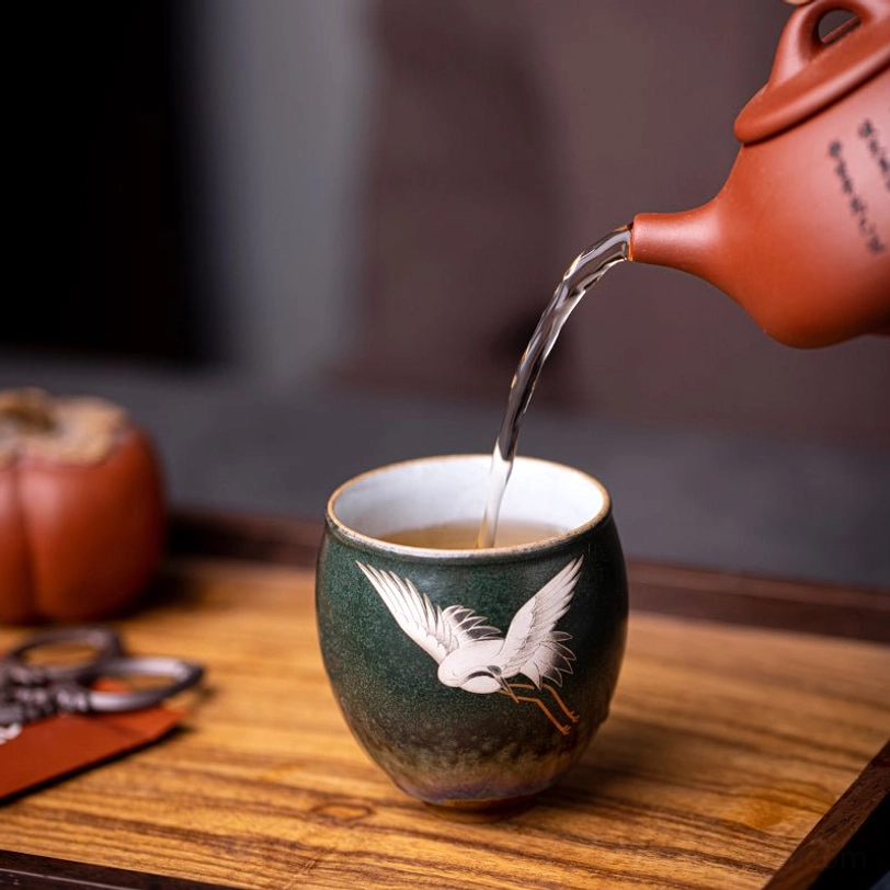 pouring tea into yellow vintage chinese ceramic crane tea cup